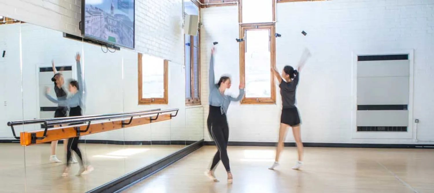 Two dancers doing ballet in front of a mirror