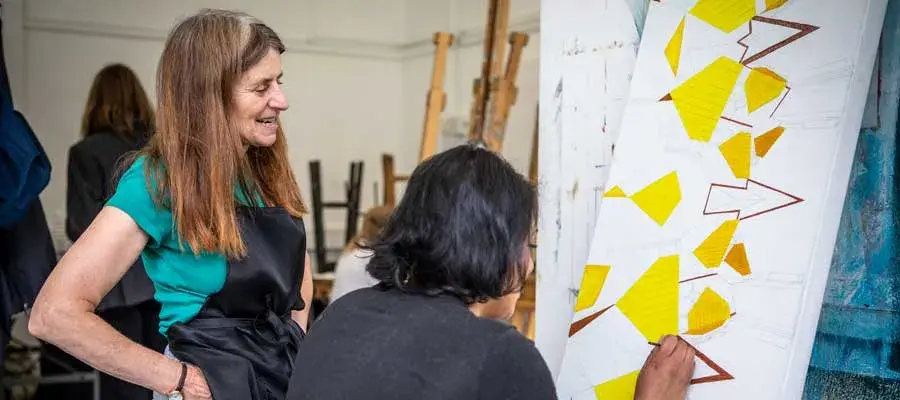 Teacher with a student who's working on a painting
