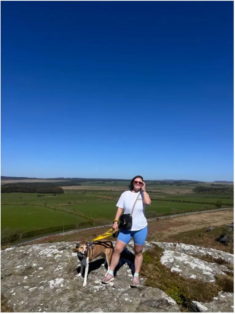 Woman standing outside on a hill with a dog