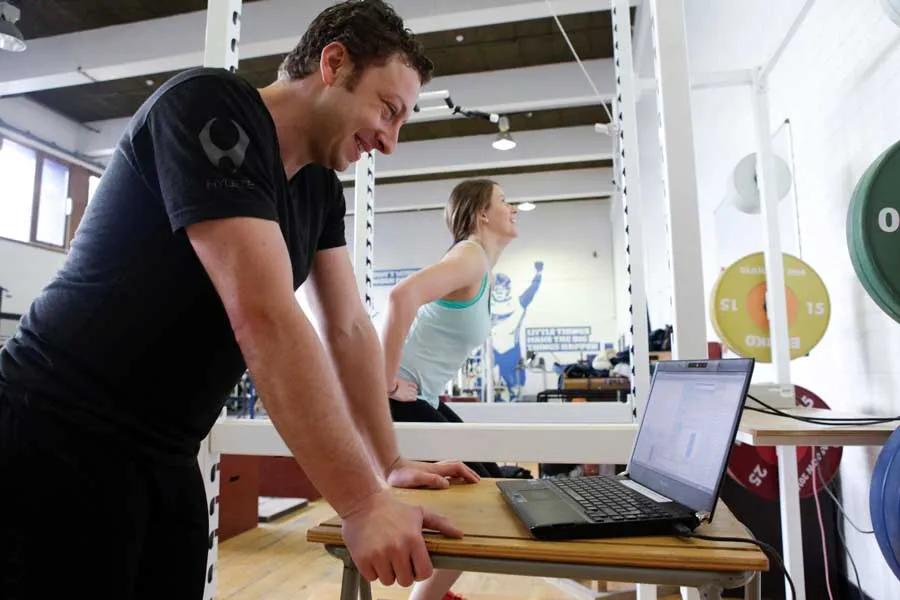 Sports researcher looking at laptop in gym