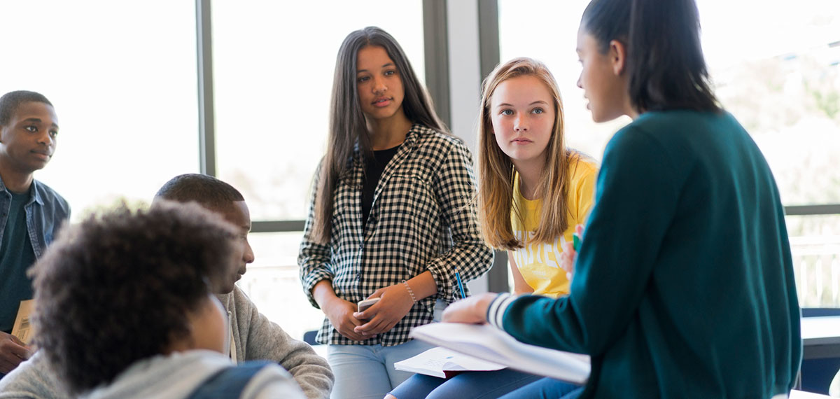 High school students are having a discussing. Multi-ethnic male and females are in classroom. 